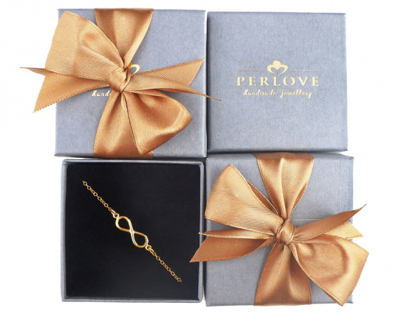Szare pudełeczka na biżuterię ze złotym logo Perlove i przewiązane złotą wstążką.